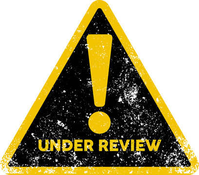 Yellow triangular warning sign with black distress texture showing the bold text under review status icon
