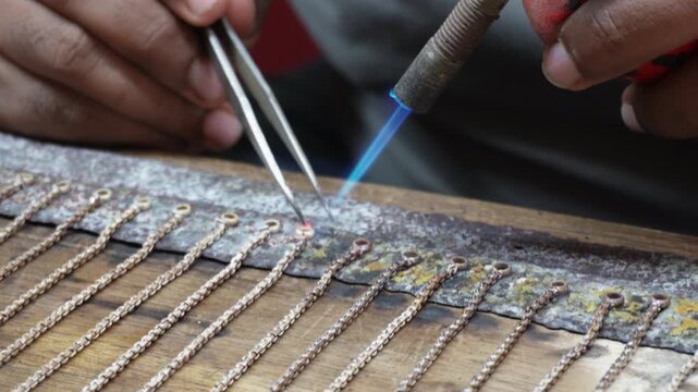 Goldsmith soldering silver chain with skilled precision