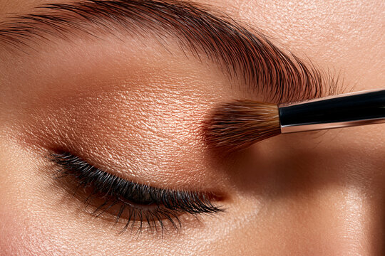 Close-up of woman applying eyeshadow makeup with brush