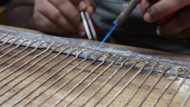 Goldsmith soldering delicate jewelry chain with torch