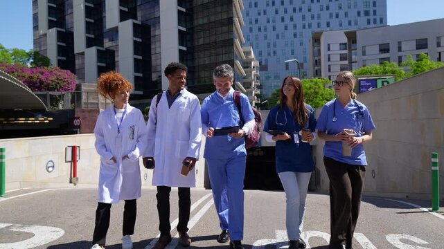 Diverse medical team of doctors and nurses walking outside hospital