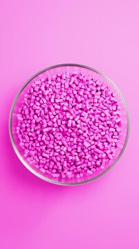 Rotating glass bowl filled with pink polypropylene plastic granules and masterbatch resin pellets on pink background, 3D render seamless Vertical video.