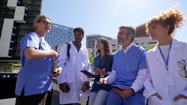 Diverse medical team discussing patient cases outside a hospital building