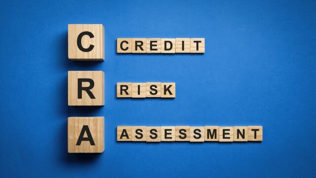 Wooden blocks spelling cra for credit risk assessment on blue background