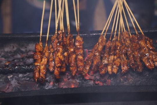 Smoky chicken satay skewers grilling over hot charcoal, showcasing authentic Indonesian street food.