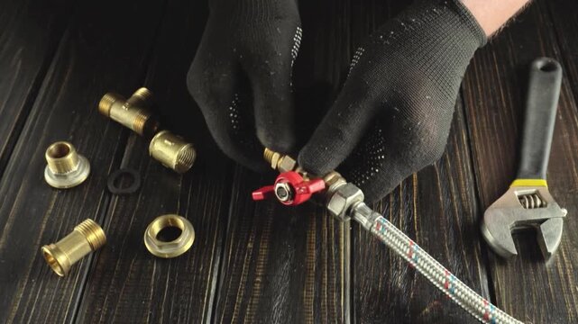 Skilled technician assembles plumbing components using a wrench and fittings on a wooden work surface, showcasing a detailed mechanical process