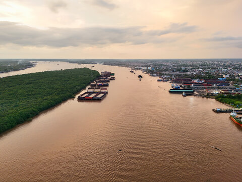 Aerial view of the Barito River with coal barges moored along the lush riverbanks near the city of Banjarmasin, Kalimantan Selatan, Indonesia.
