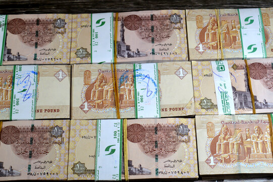 multiple stacked bundles of 1 Egyptian Pound banknotes, The bundles are secured with green currency straps, often bearing the logo of the National Bank of Egypt