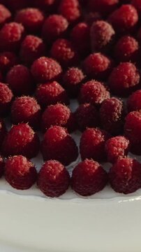 Vertical video. Macro shot of ripe raspberries arranged on top of a wedding cake for a celebration.