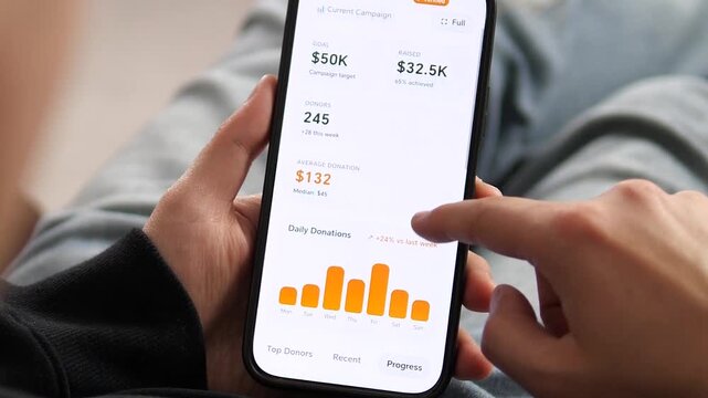 Close-up of a mobile donation tracker app. User scrolls through daily donation charts, payment methods, and geographic data. Ideal for crowdfunding software demos, digital philanthropy, and financial