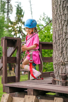 The child fastens a carabiner to the safety rope before completing the rope course with obstacles.