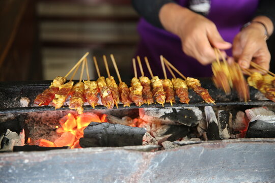 Chicken satay grilling over hot charcoal with smoky flames, authentic Indonesian street food freshly cooked on skewers, perfect for culinary and travel photography.