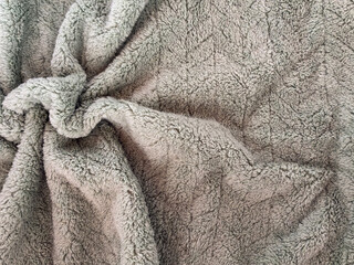Soft gray fleece blanket with fluffy plush texture and natural folds, suitable as cozy textile background for home comfort, warmth, winter lifestyle, bedding, fabric, and interior design concepts. © DaceSn