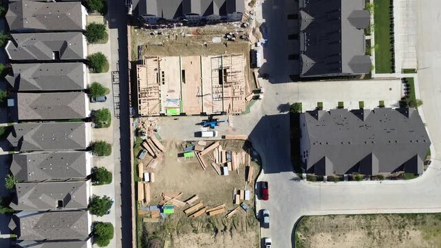 Structural framing work continues within growing Vue Las Colinas residential development. Pristine roof planes border unpaved construction areas bathed in warm light over city in Irving, Texas