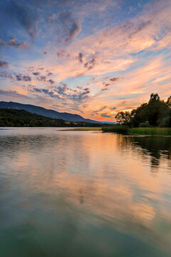 Scenic landscape of Sobron reservoir featuring mountain reflections in the calm water with green forests and a dramatic sky in northern Spain