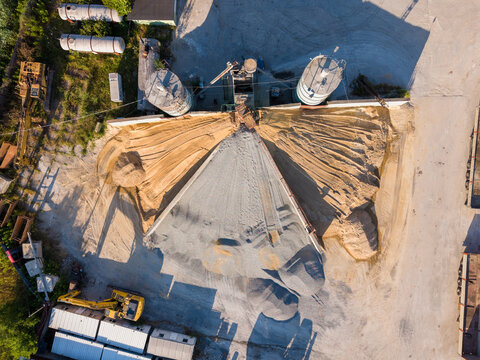 Aerial view of an industrial gravel and sand processing facility with large storage silos, piles of aggregate, and heavy machinery in Ravadinovo, Burgas, Bulgaria.