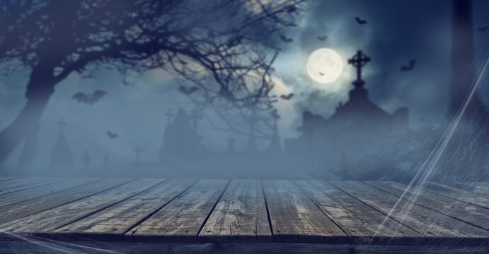 Horror or Halloween stage background with old wooden surface and horror and Halloween attributes in the background.