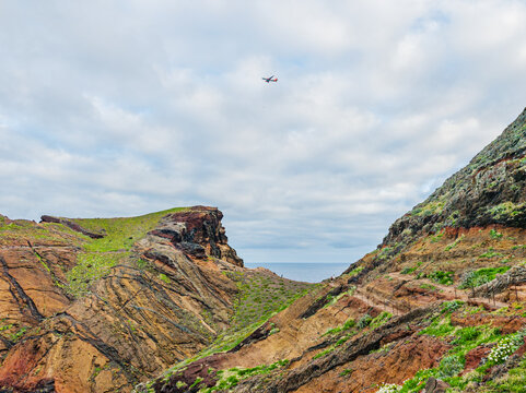 A high-angle view of the deep blue sea meeting a distant flat rocky island from the slopes of Ponta de Sao Lourenco, Madeira, Portugal.