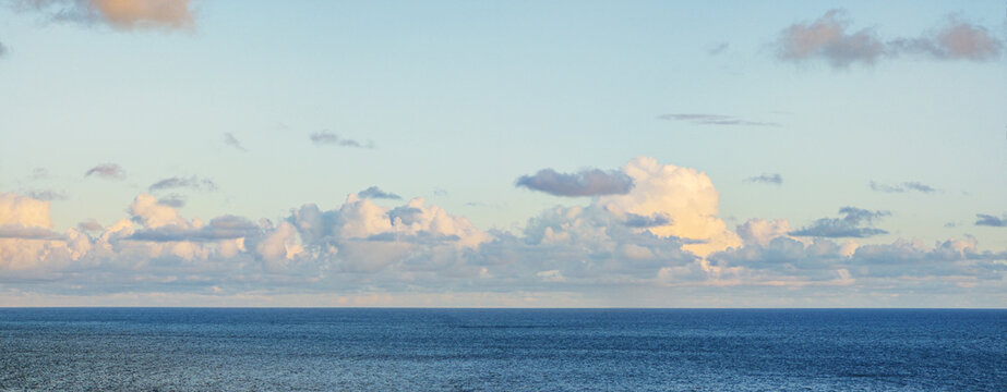 A vast landscape view of the deep blue Atlantic Ocean meeting the horizon under a wide sky with wispy clouds, Madeira, Portugal.
