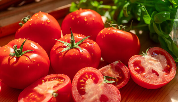 Fresh red tomatoes and slices with green leaves