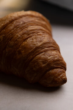 Croissant artesanal de mantequilla sobre papel para hornear con textura hojaldrada y enfoque selectivo