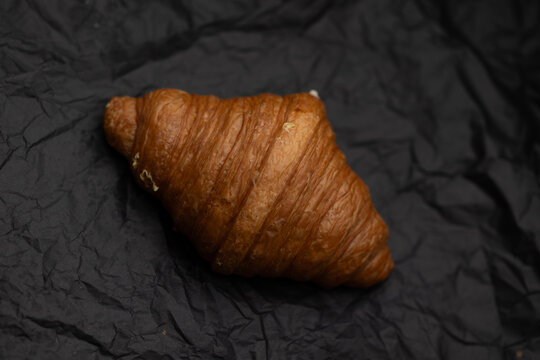 Croissant artesanal de mantequilla sobre papel para hornear con textura hojaldrada y enfoque selectivo