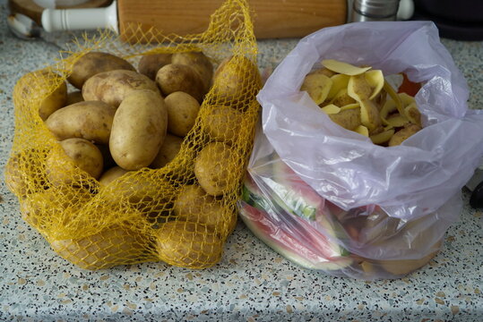 Potatoes in mesh bag and potato peels in plastic bag