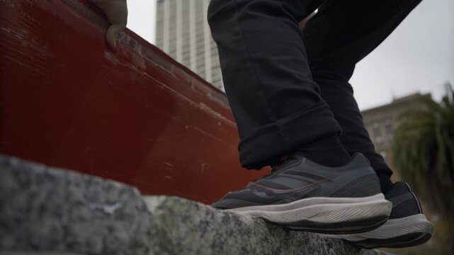 Sneakers Jumping onto Stone Ledge - Low Angle Close-Up In Plaza