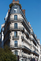 Striking close-up of a curved corner Haussmann building on the Rue du Quatre-Septembre in Paris, its stacked ornate wrought-iron balconies sweeping elegantly around the rounded angle. © kovalenkovpetr