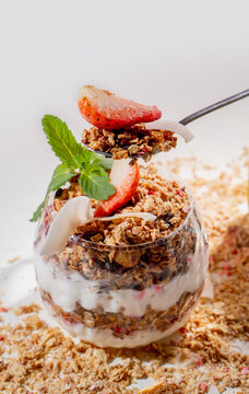 Healthy Granola Yogurt Parfait with Fresh Strawberry, Mint and Coconut Flakes on Pink Background