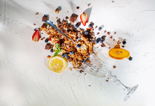 Creative Flat Lay of Granola with Fresh Fruits, Yogurt and Chocolate on White Background