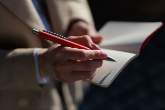 businesswoman writes notes during a meeting outside on a sunny day in the city