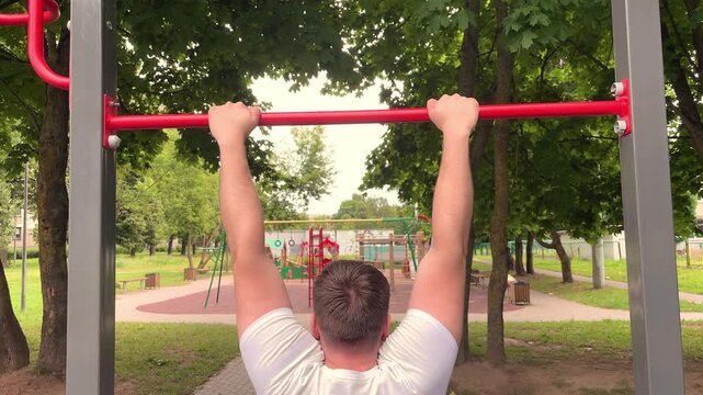 Man training upper body on pull-up bar in a park