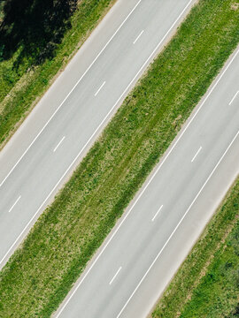 Aerial view of the A2 highway with two parallel lanes separated by a grassy median strip under bright daylight in Riga, Adazi Municipality, Latvia.