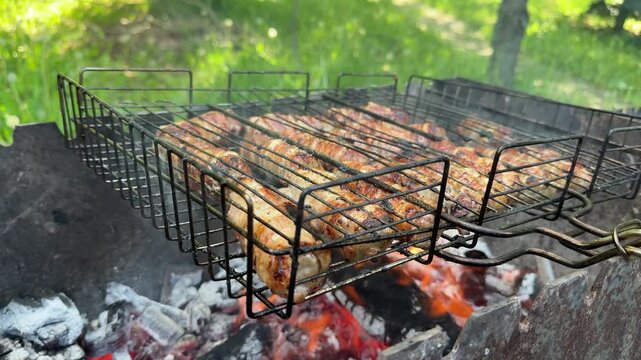 Crispy bacon wrapped sausages grilling on metal grate above hot fire during outdoor picnic cooking with cozy barbecue atmosphere in nature.