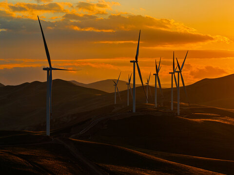 Beautiful sunset field with wind mill generators. Windmill silhouette on mountain at sunset