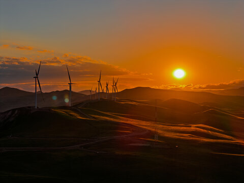 Beautiful sunset field with wind mill generators. Windmill silhouette on mountain at sunset