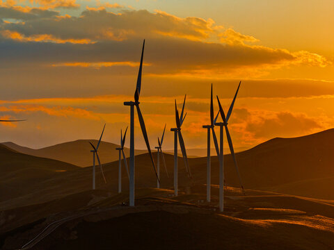 Beautiful sunset field with wind mill generators. Windmill silhouette on mountain at sunset