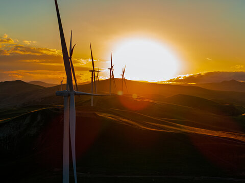 Beautiful sunset field with wind mill generators. Windmill silhouette on mountain at sunset