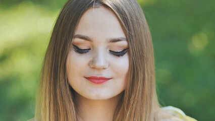 Naklejka premium Portrait of a young girl in a park. Close-up of her face.