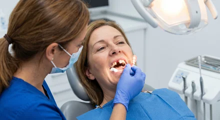 Dentist placing a temporary removable partial denture flipper tooth into a patient's mouth to fill a missing front tooth gap. © juanorihuela