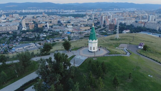 Aerial view of paraskeva pyatnitsa chapel on karaulnaya hill, providing a scenic overlook of krasnoyarsk city during sunset