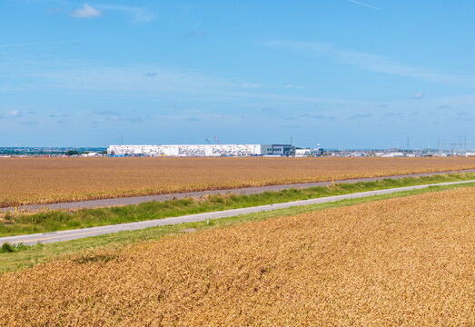 Large AI data center in Hutto, Texas, near Austin, set in rural area with heat haze from the farmland crops blurring the view of the construction