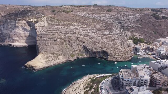Aerial view of Xlendi Bay featuring the historic watchtower on the rocky cliffs and coastal buildings in Munxar, Gozo Region, Malta. High quality 4k footage