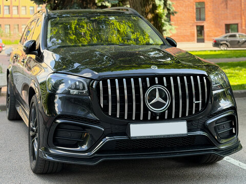 Black Mercedes-Benz GLS luxury SUV parked on a city street with chrome grille on outdoor parking lot. Modern black Mercedes-Benz GLS luxury SUV car parked outdoors. 