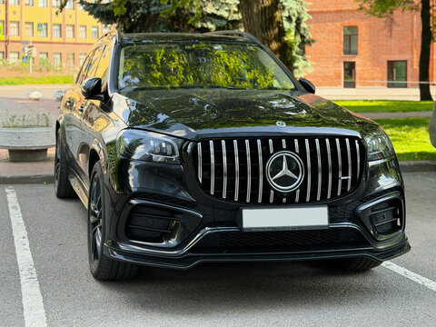 Black Mercedes-Benz GLS luxury SUV parked on a city street with chrome grille on outdoor parking lot. Modern black Mercedes-Benz GLS luxury SUV car parked outdoors. 