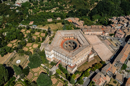 Aerial view of the pentagonal Villa Farnese with its central circular courtyard, surrounded by manicured Renaissance gardens and the historic town of Caprarola, Lazio, Italy.