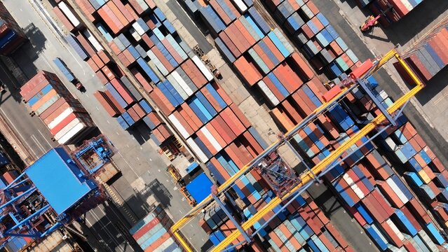 Aerial perspective of container ship loading operations, highlighting maritime cargo handling at busy industrial harbor