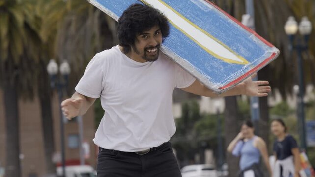 Man Carrying Blue Cross Board And Doing Tricks In San Francisco Plaza - Medium, Slow Motion Shot
