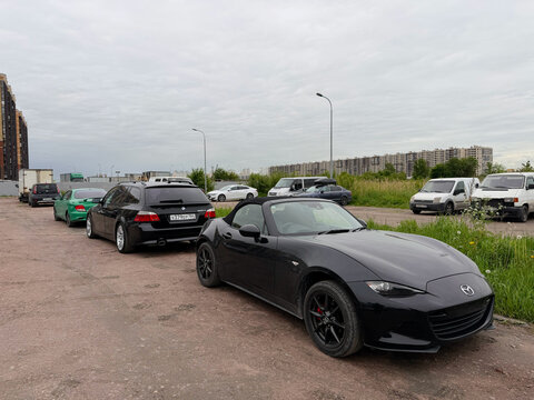 A stylish Mazda MX-5 RF Miata Sport Tech, two door sports car convertible black color, in a carpark at the city. Exterior of a Mazda MX-5 Miata RF Roadster fastback model. JDM car. 